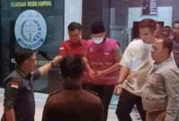 Tersangka MF (baju rompi bermasker) keluar dari gedung Kejari Sampang dan digelandang ke mobil tahanan, pada Kamis (27/8/2026) malam