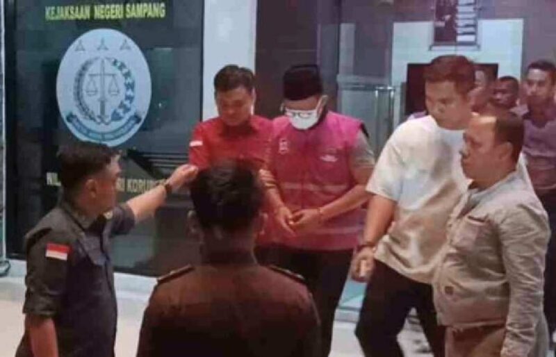 Tersangka MF (baju rompi bermasker) keluar dari gedung Kejari Sampang dan digelandang ke mobil tahanan, pada Kamis (27/8/2026) malam